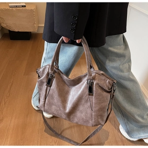 Detail of the litchi texture leather tote with adjustable shoulder strap on a model