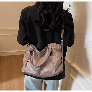 Detail of soft wrinkled bronze tote bag with adjustable straps on a female model
