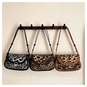 Detailed view of leopard print shoulder bags in three colors with metal buckle closure