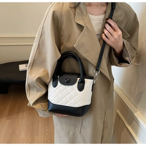 Borsa a tracolla trapuntata bianca e nera indossata da una modella per la scala