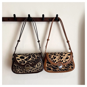Detail view of leopard print shoulder bags featuring metal buckles and faux fur texture