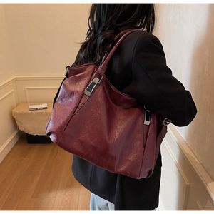 Burgundy faux leather tote bag with silver hardware worn by a model in a minimalist setting