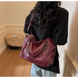 Model view of a large burgundy tote bag with pleated texture and adjustable strap