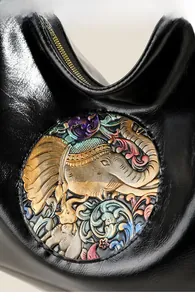 Detail of colorful elephant relief pattern on black leather backpack with metal zipper