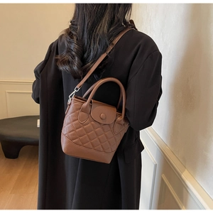 Borsa a secchiello in pelle trapuntata marrone indossata da modella con tracolla regolabile