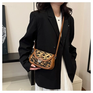 Close-up of leopard print crossbody bag with metal lock worn on model over black blazer