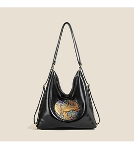 Detail of black glossy leather bag with colorful ethnic elephant pattern embroidery