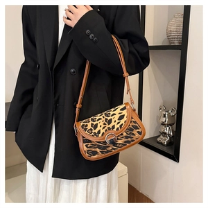 Close-up of leopard print shoulder bag with brown leather trim and silver metal clasp