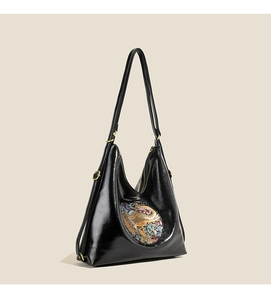 Detail of black hobo shoulder bag featuring vibrant circular embossed floral pattern and gold hardware