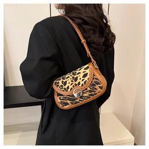 Detail of leopard print handbag with leather trim and silver round metal buckle on shoulder