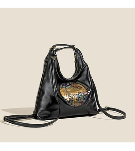 Detail of glossy black leather tote bag featuring a colorful elephant relief pattern
