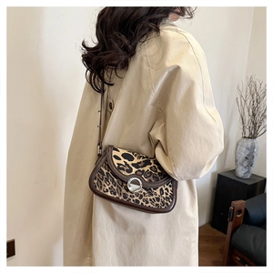 Close-up of leopard print shoulder bag with silver buckle worn with a beige trench coat