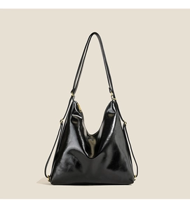 Detailed view of the glossy black leather bag with gold-tone hardware and smooth texture