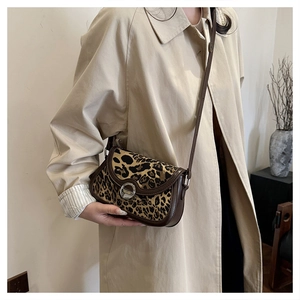 Detail of leopard print crossbody bag with brown leather trim and silver metal lock buckle