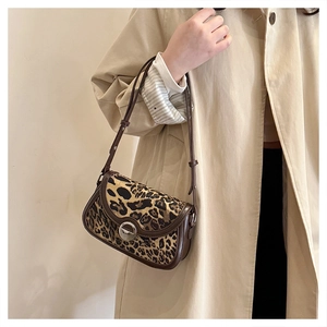 Detailed view of the leopard print shoulder bag featuring leather trim and silver metal clasp