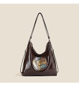 Detailed close-up of dark brown leather tote with a decorative elephant embossed plate