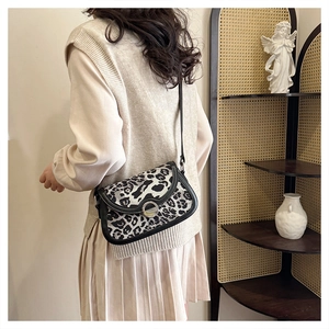Detail showing leopard print saddle bag with ring buckle on a model for scale