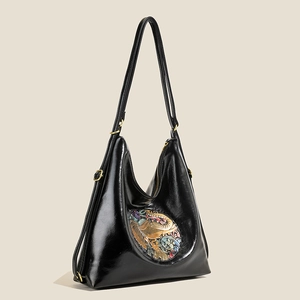 Elegant black glossy tote bag with vintage embossed patch and adjustable strap