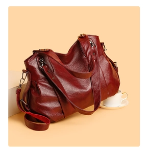 Macro detail of dark red large tote bag featuring soft grainy leather and pleated design