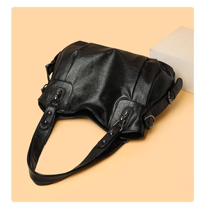 Detailed view of black PU leather shoulder bag featuring layered pleats and metal rivets
