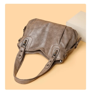 Detail of vintage taupe PU leather tote bag featuring wrinkled texture and bronze rivets