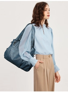 Detail of navy blue large PU leather tote showing side metal buckle and reinforced stitching