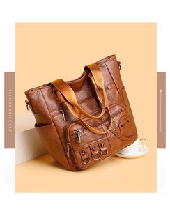 Close-up of vintage brown PU leather tote with zipper pockets and decorative rivets