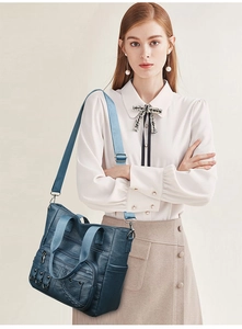 Detail of dark blue faux leather tote bag with multiple zip pockets and woven straps