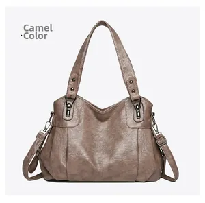 Detail showing the retro pleated leather texture and grey hardware on a camel tote bag