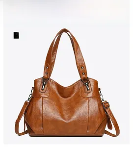 Close-up of brown PU leather tote bag texture with adjustable strap and metal hardware