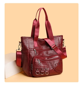 Close-up of wine red leather tote with multiple zipper pockets and woven metal details