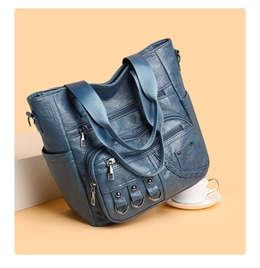 Detail view of the vintage blue faux leather tote with functional zippers and woven patterns