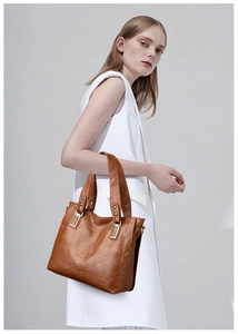 Brown faux leather tote bag with vertical stitching and metallic rivet details