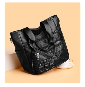 Close-up of black leather tote bag featuring multiple zipper pockets and lychee texture
