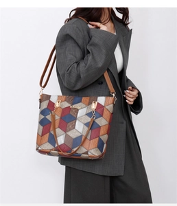 Crossbody view of geometric pattern tote bag with leather texture and 3D color blocks