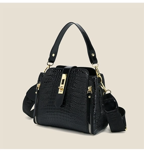 Close-up of black crocodile pattern patent leather bag with gold square rotary lock