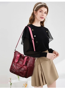 Detail view of burgundy faux leather shoulder bag with multiple zippers and pink strap