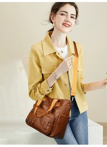 Brown vintage leather tote with multiple zip pockets and adjustable nylon strap on model