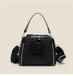Detail of black faux crocodile leather handbag with wide woven strap and silver zippers