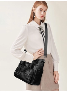 Close-up of black multi-pocket tote bag with silver zippers and wide fabric strap