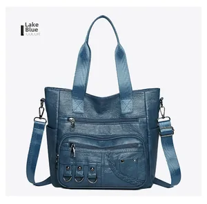 Detail of lake blue shoulder bag showing textured PU leather and zipper pockets