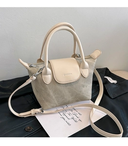 Détail du sac seau en toile grise avec rabat en cuir crème et logo embossé élégant