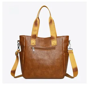 Back view of brown faux leather tote bag with fabric strap and zip pocket detail