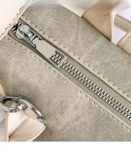 Gros plan sur les fermetures éclair argentées et les détails du tissu sur le sac seau