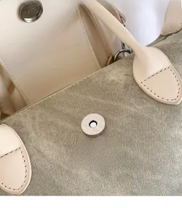 Gros plan sur la boucle magnétique argentée d'un sac seau en toile aux coutures soignées