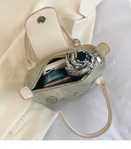 Vue de dessus de l'intérieur spacieux du sac seau en toile vert sauge avec objets essentiels