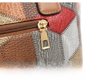 Detail of color-block tote bag featuring textured leather and a golden metal zipper