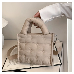 Detail der beige gesteppten Daunentasche mit verstellbarem Gurt und Tragegriff