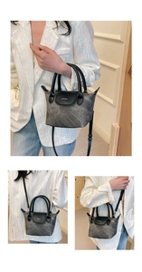 Détail de la texture grise et de l'anse en cuir noir sur un sac seau chic et compact
