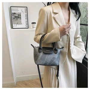 Détail du petit sac seau gris avec poignée et bandoulière en cuir noir élégant